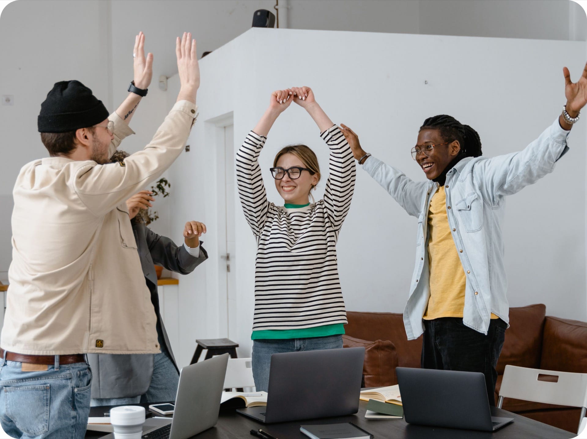 Coworkers cheering with their arms raised in an office